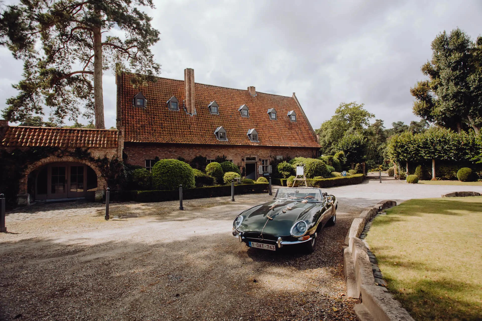 Oldtimer cabriolet op de oprit voor de voorgevel van de kasteelhoeve