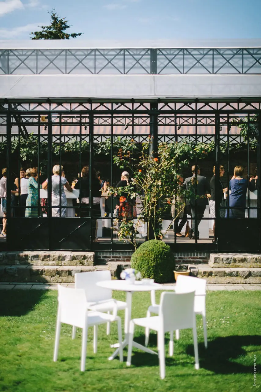 Witte tuintafel op het gazon voor de orangerie vol gasten