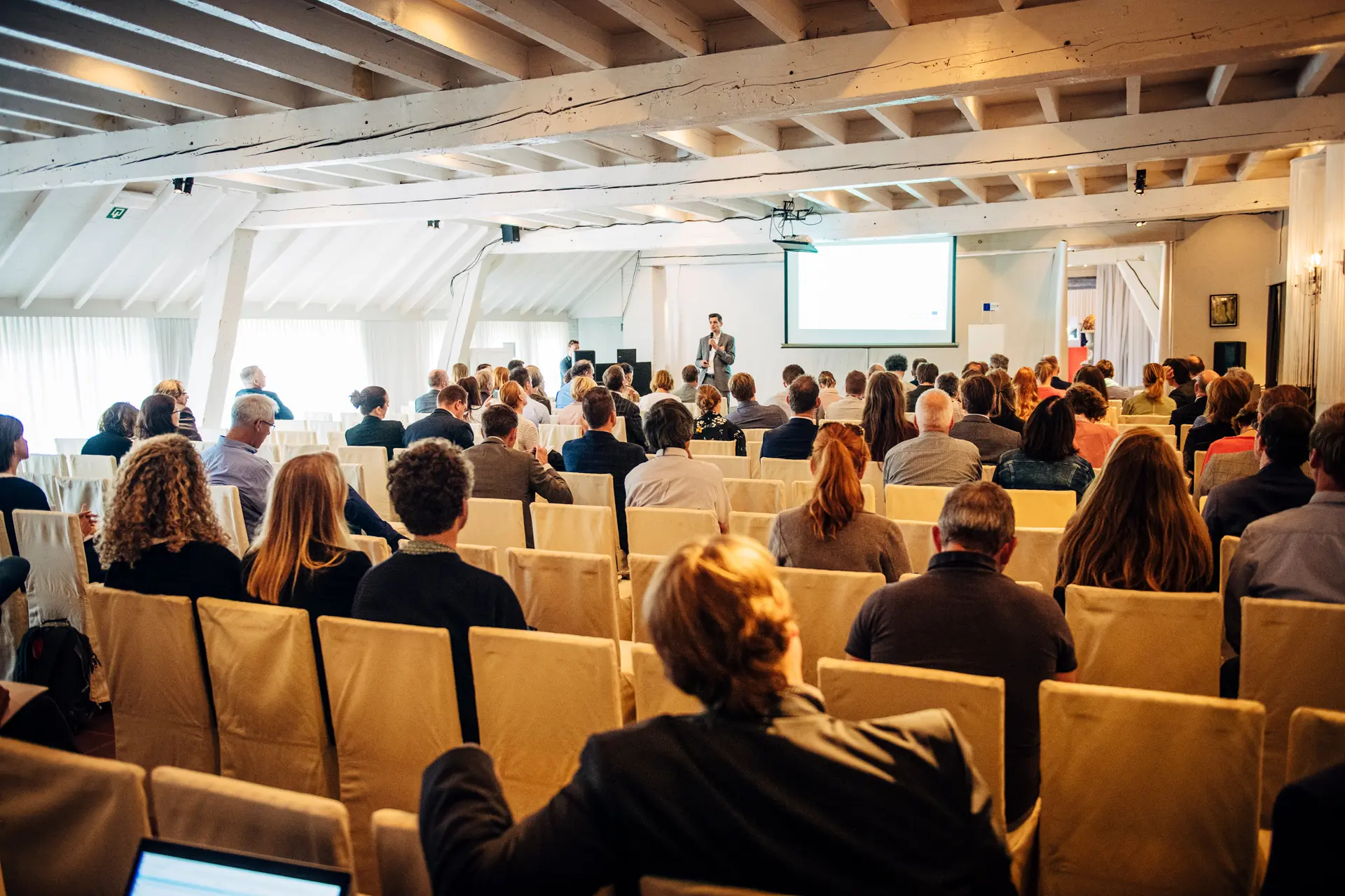 Zaal in theateropstelling tijdens een presentatie