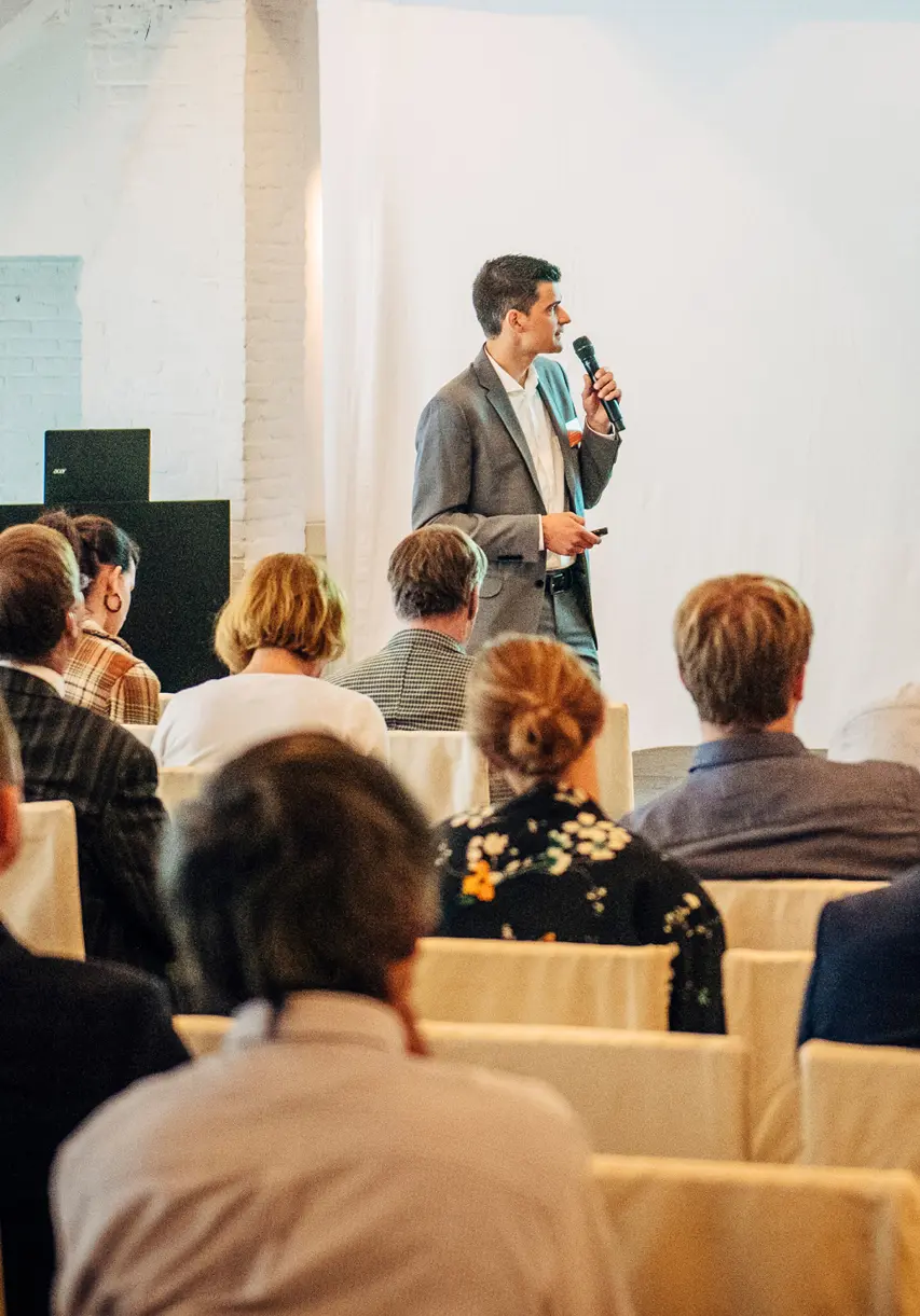 Spreker met microfoon tussen het publiek tijdens een zakelijke keynote