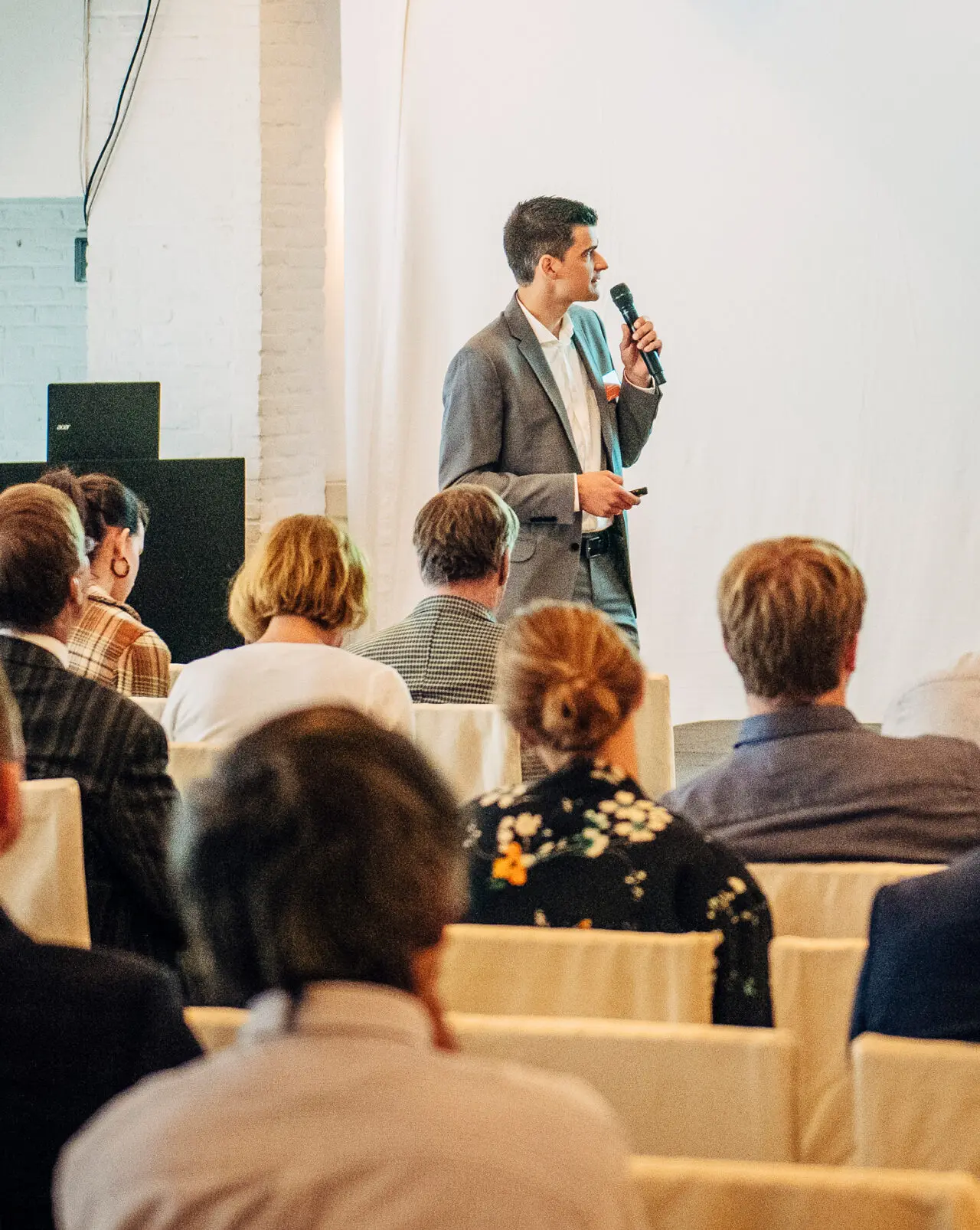 Spreker met microfoon voor een volle zaal tijdens een bedrijfsevent