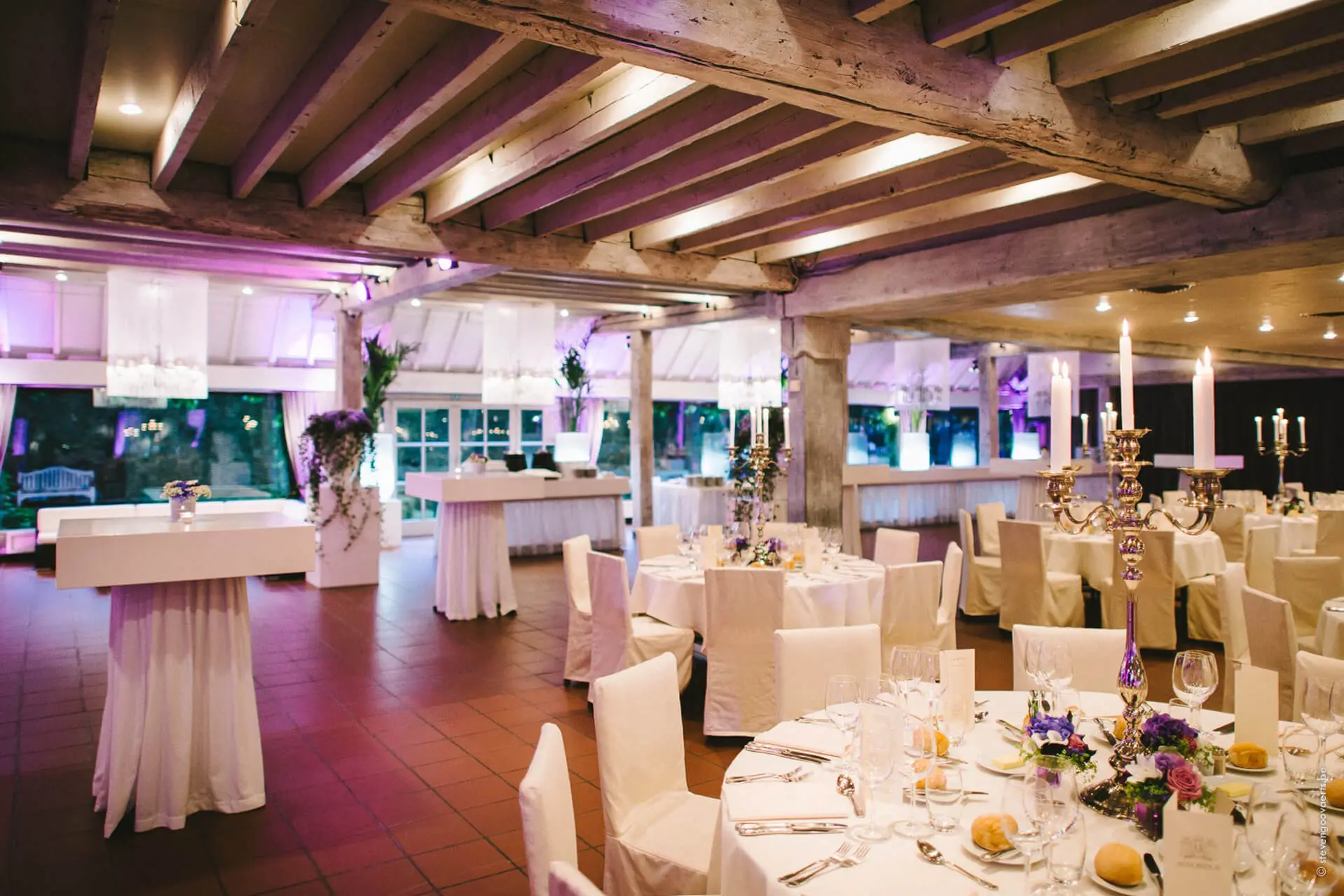 Aangeklede grote zaal met hoge tafels en gedekte ronde tafels