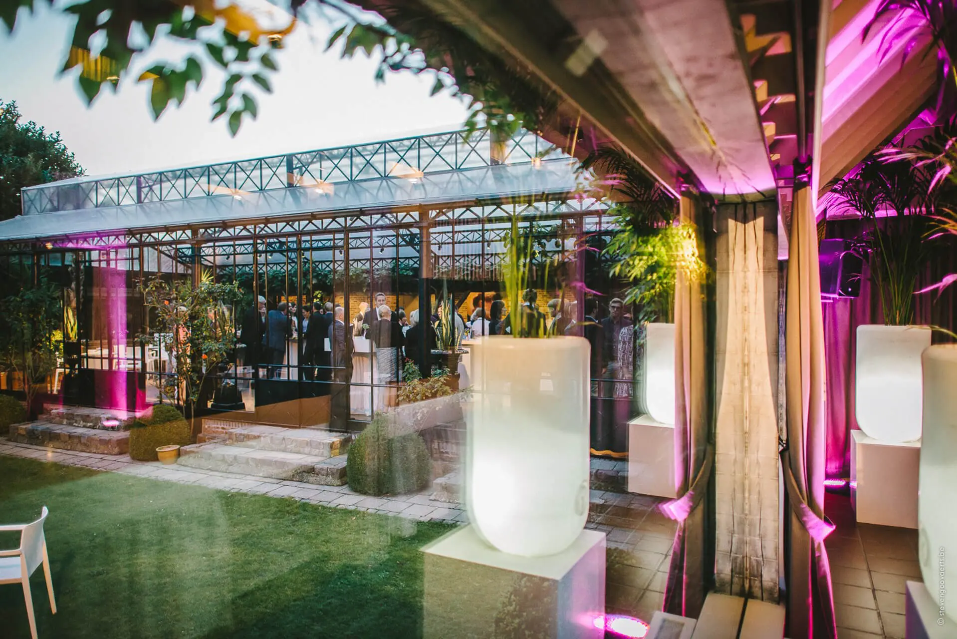 Verlichte orangerie van de grote zaal in de avond, gezien vanuit de tuin