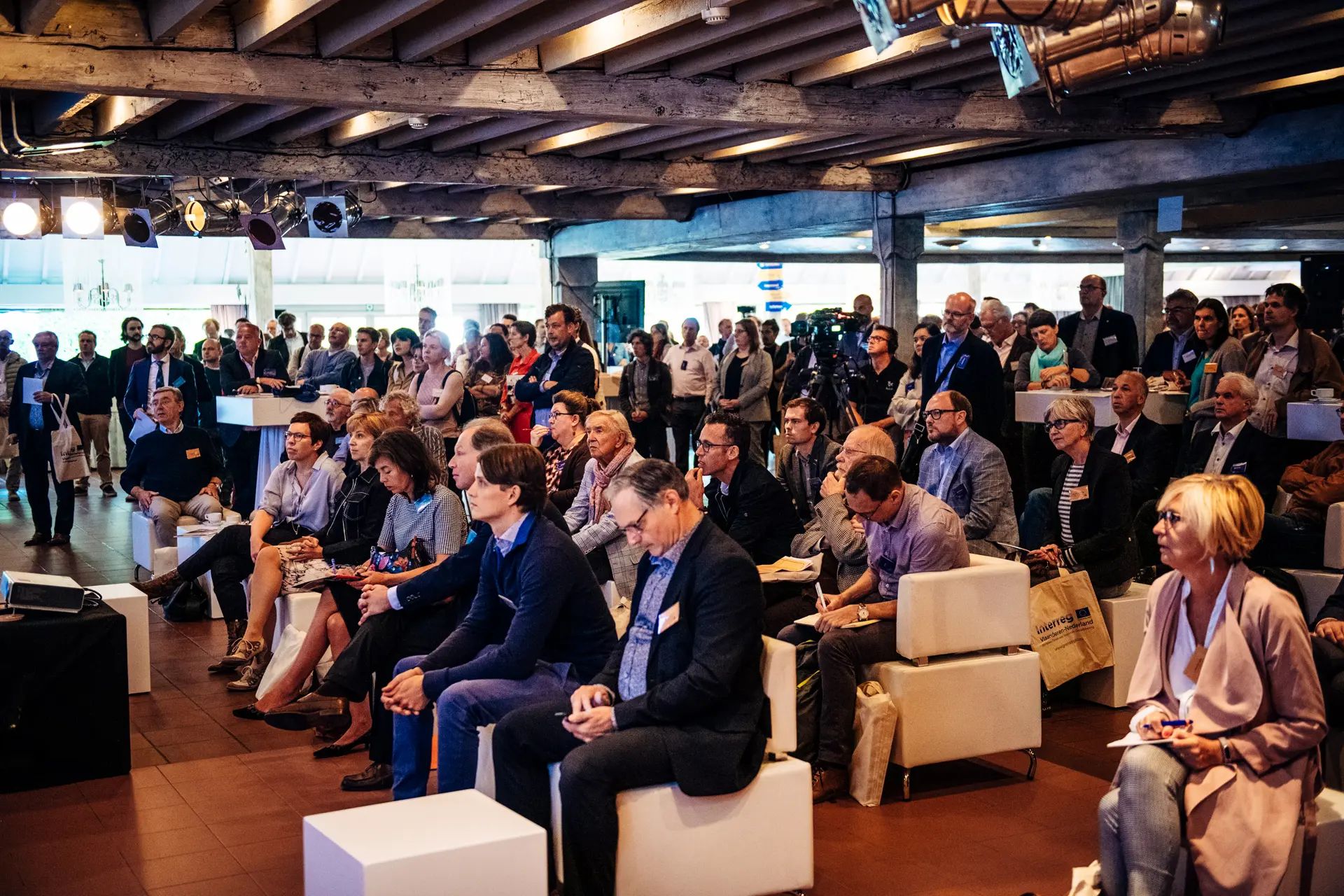 Publiek volgt een presentatie in de zaal