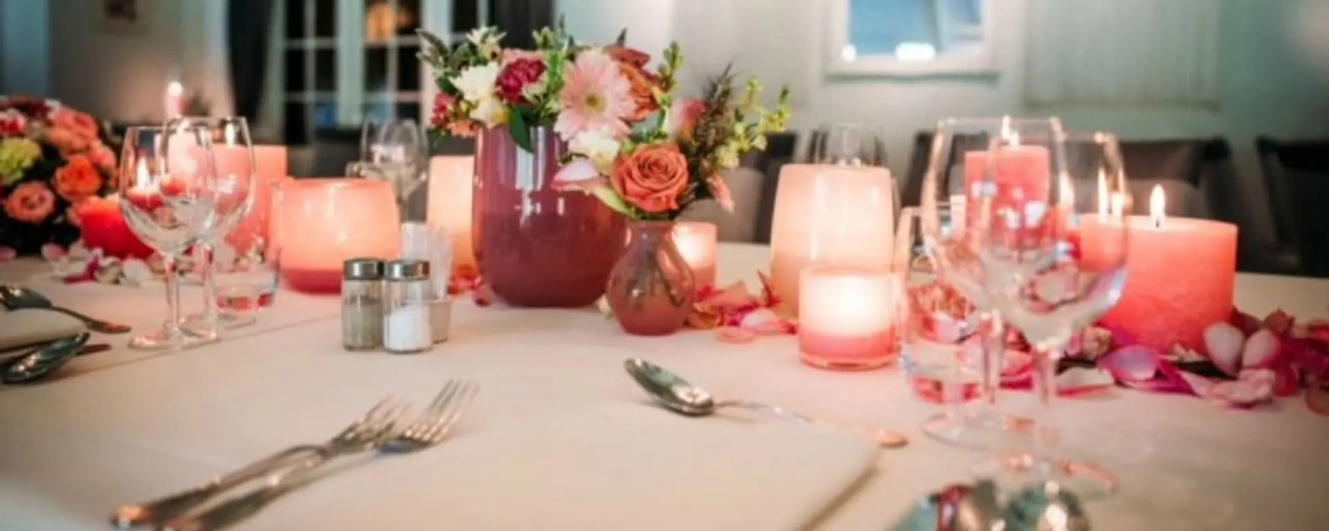 Tafeldecoratie met roze kaarsen en bloemen