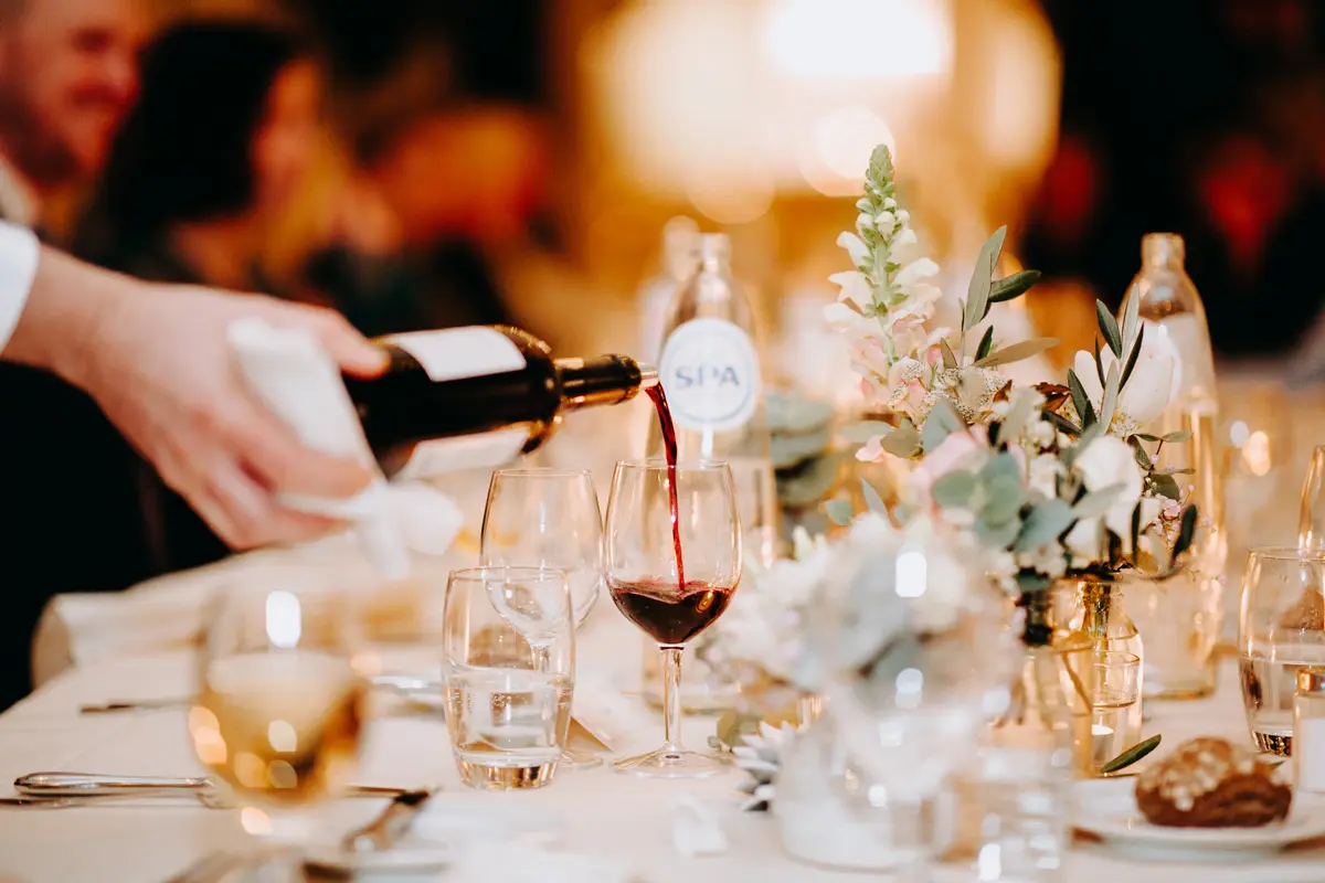 Rode wijn wordt ingeschonken aan een feestelijk gedekte tafel