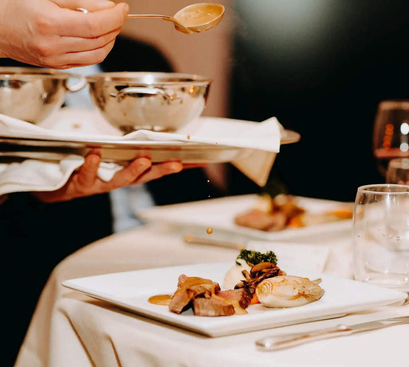 Saus wordt aan tafel over het gerecht geschept