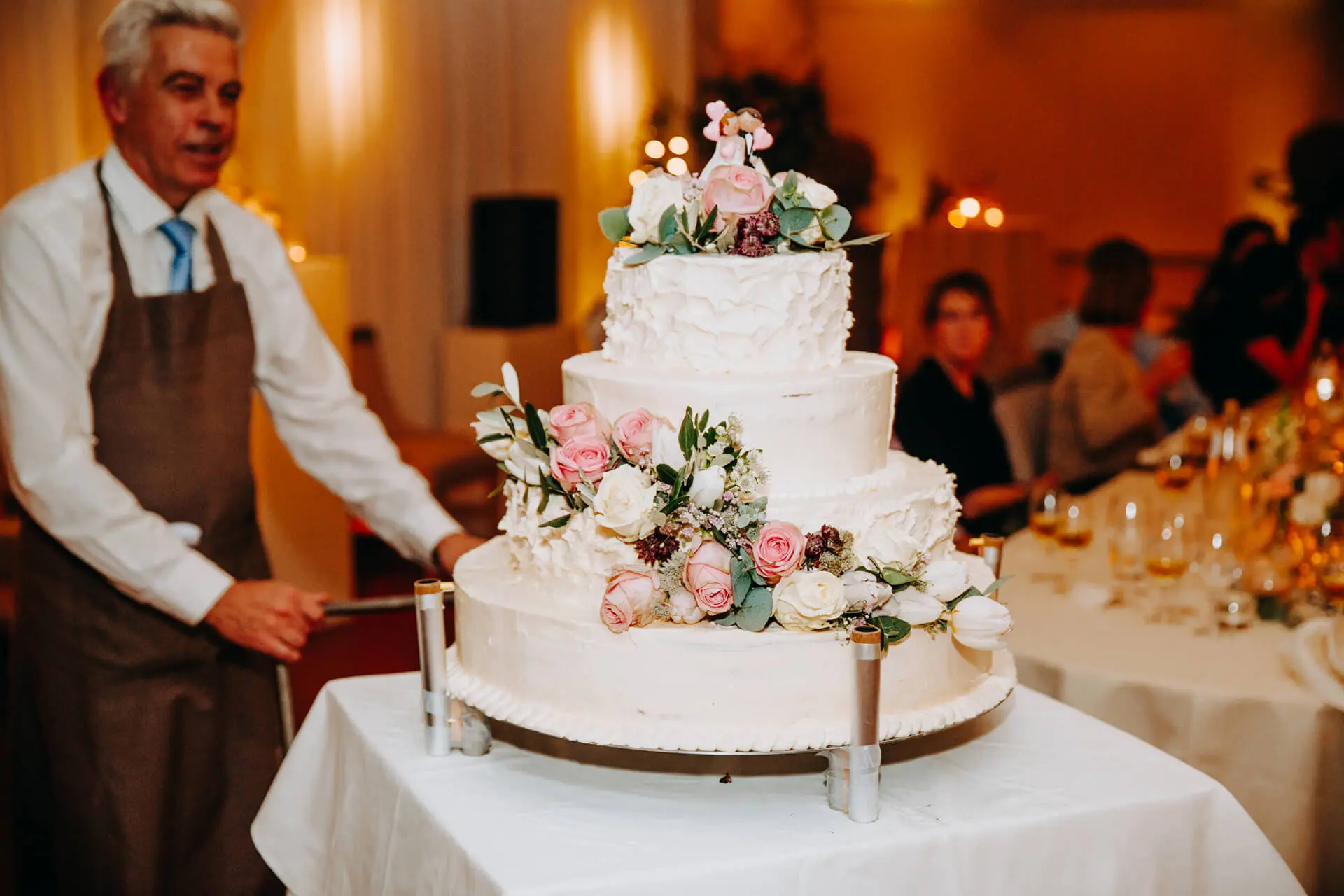 Bruidstaart met bloemen wordt de zaal binnengebracht