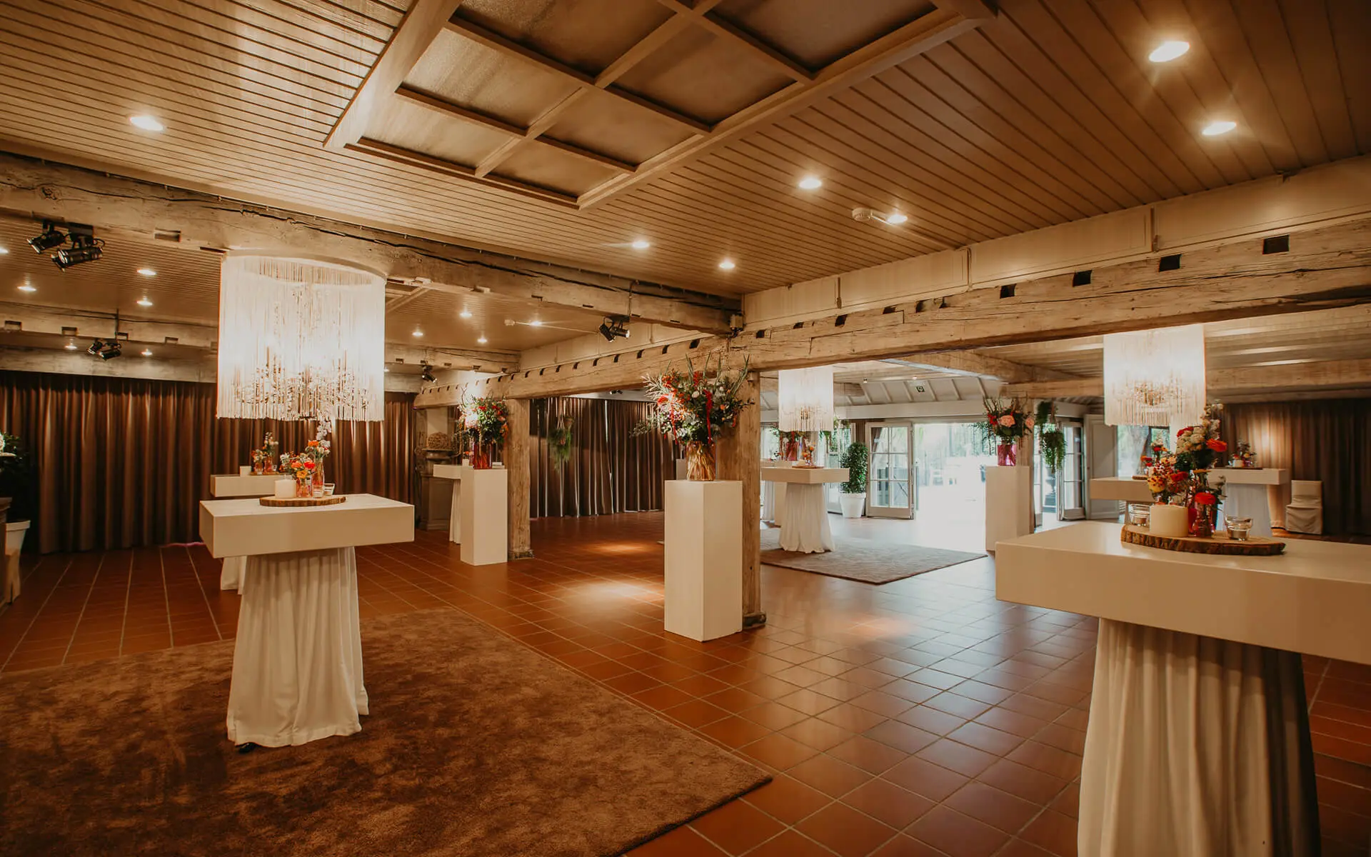Aperitiefgedeelte van de grote zaal met hoge tafels en kroonluchters