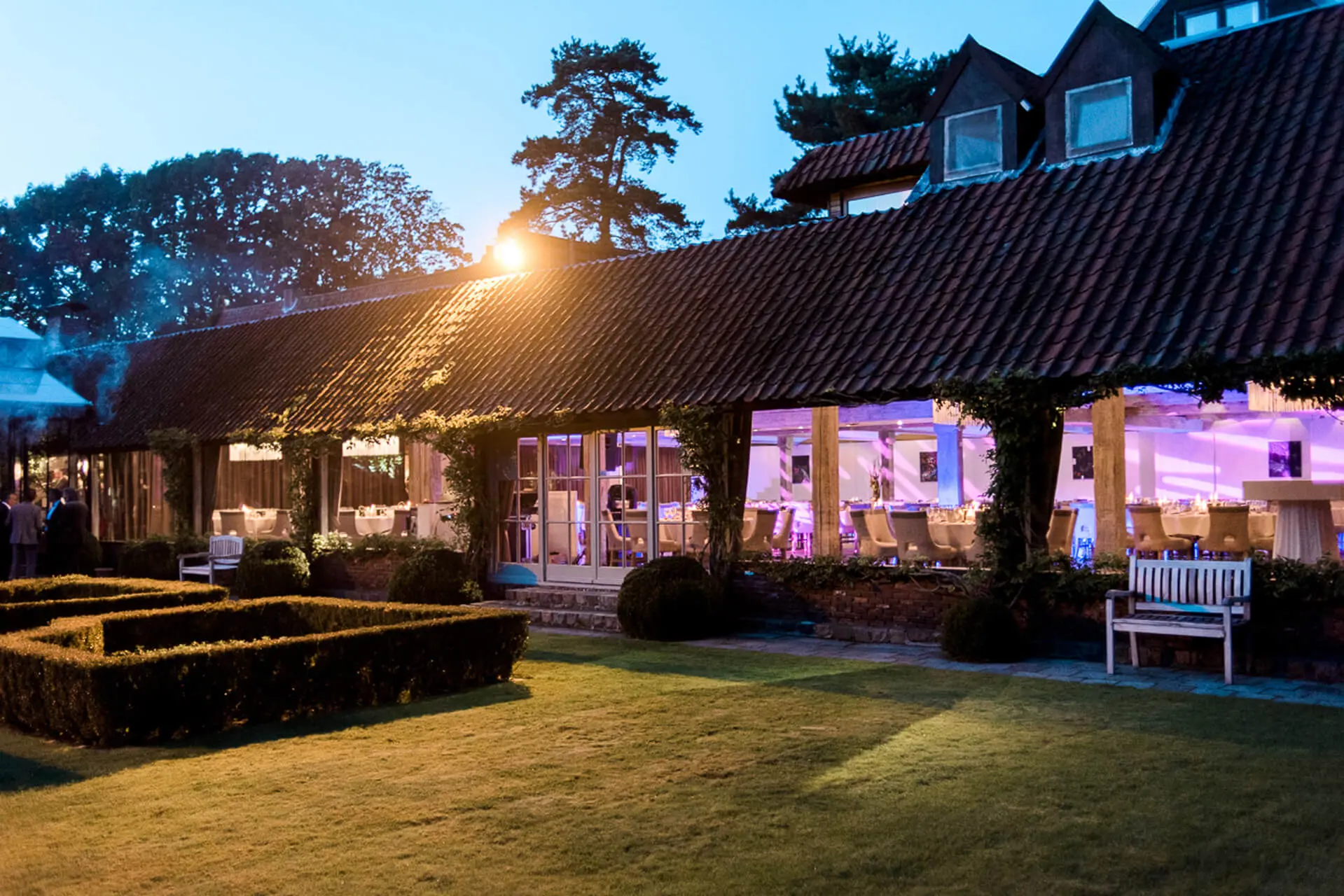 Verlichte kasteelhoeve en tuin bij valavond tijdens een avondfeest