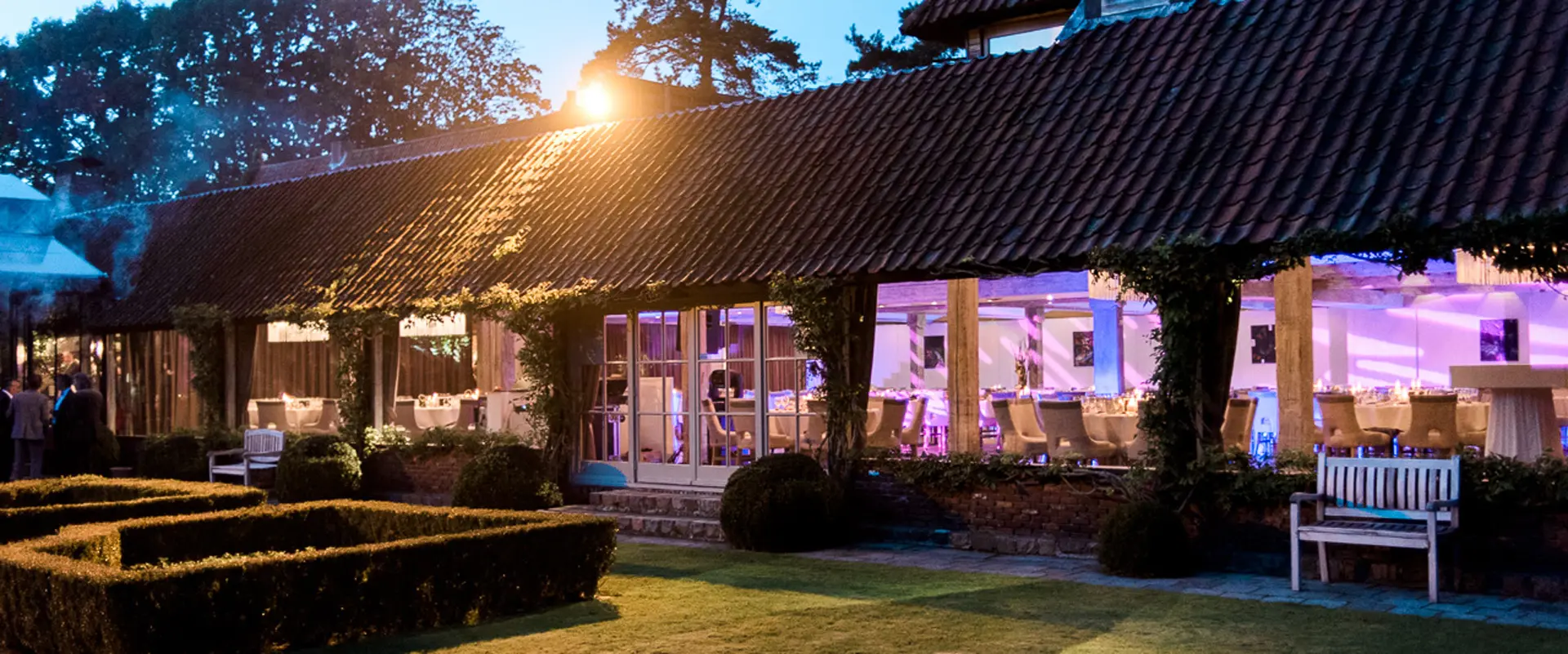 Verlichte kasteelhoeve en tuin bij valavond tijdens een avondfeest