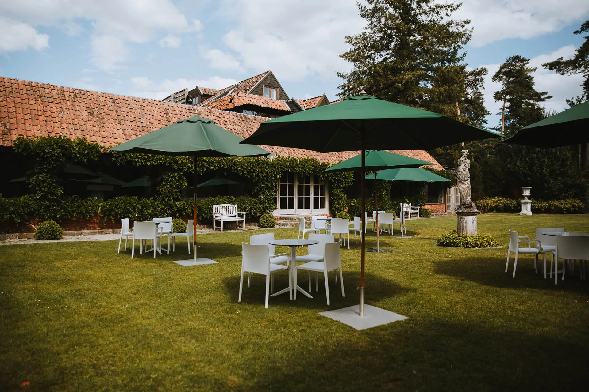 Tuin met witte tafels en stoelen onder groene parasols