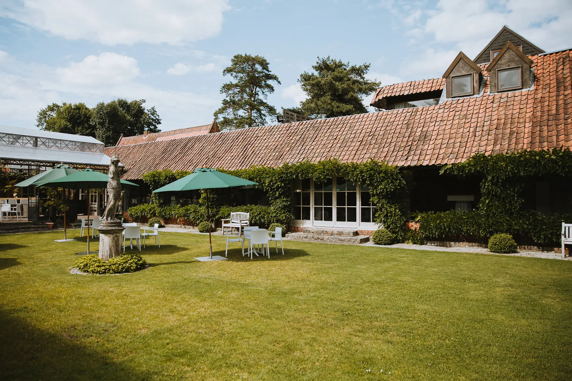 Tuin van de grote zaal met gazon, parasols en de kasteelhoeve