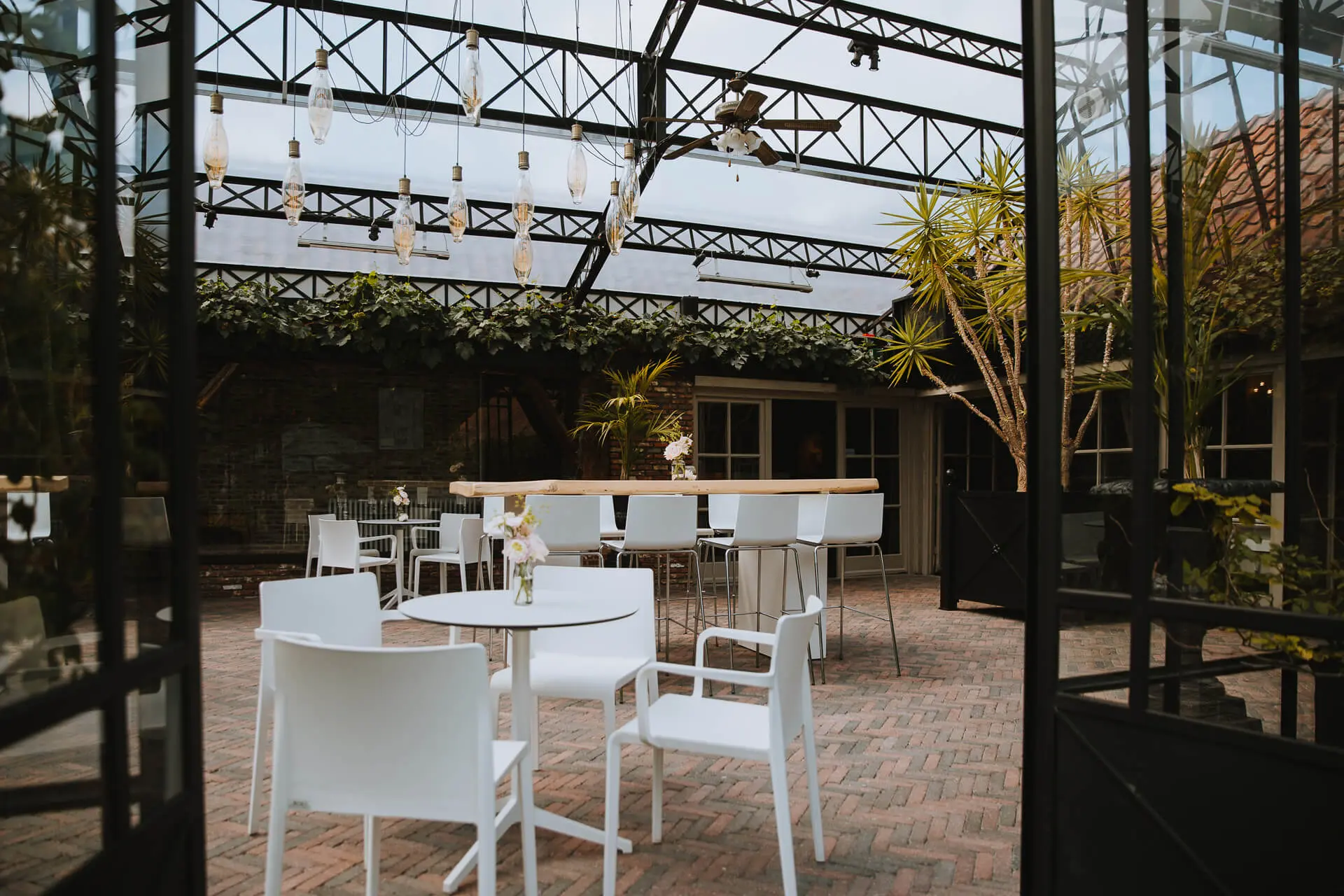 Witte tafels en stoelen in de orangerie van de grote zaal, gezien door de open deuren