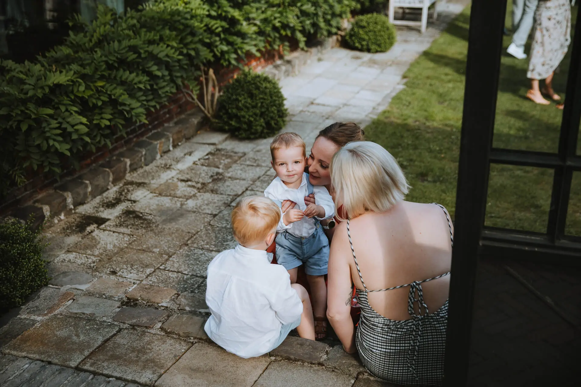 Moeder zit met twee kleine kinderen op het tuinpad