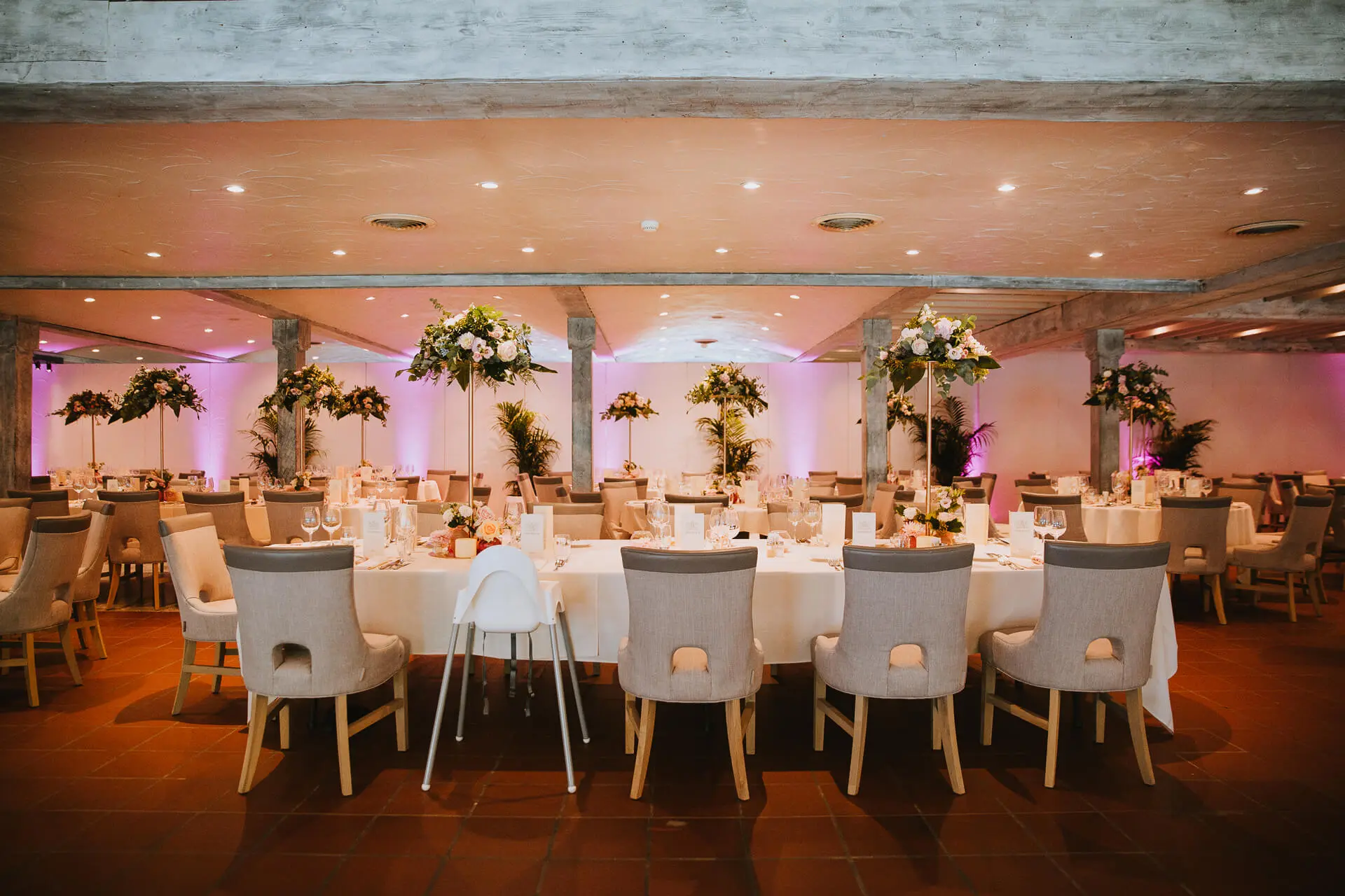 Eretafel met bloemstukken in de grote zaal, met een kinderstoel in het midden