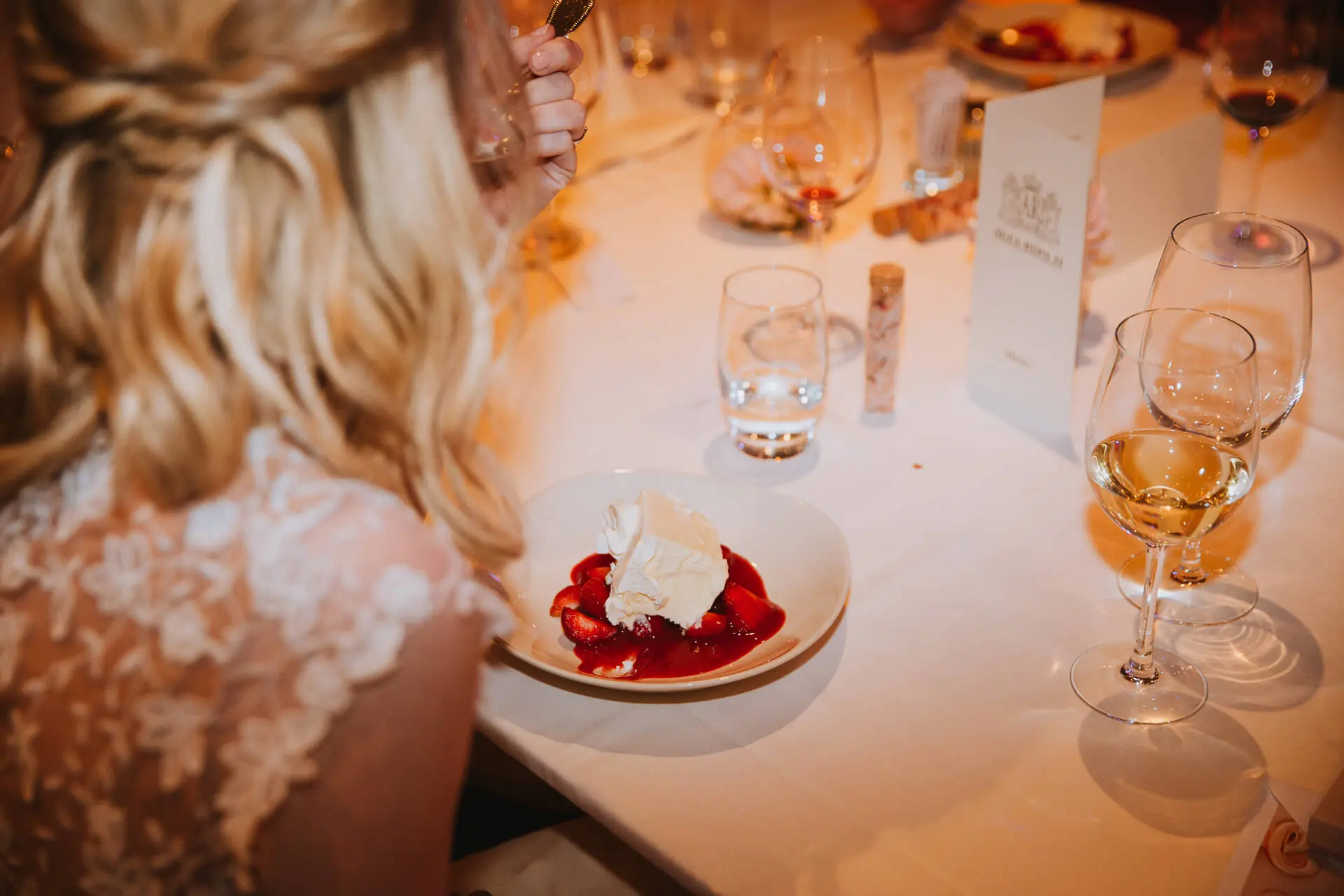 Bruid aan tafel met een dessert van ijstaart en aardbeien