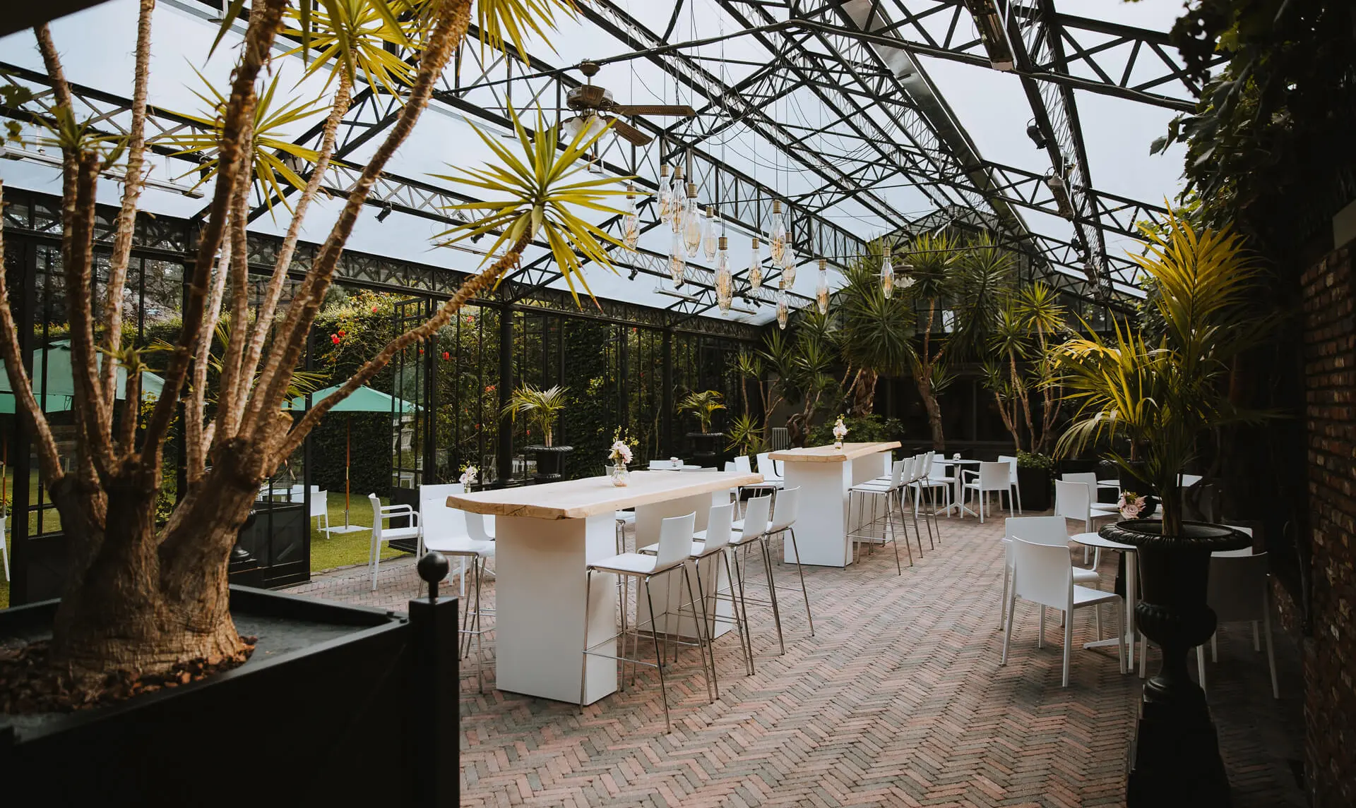 Orangerie van de grote zaal met hoge tafels, witte stoelen en palmen