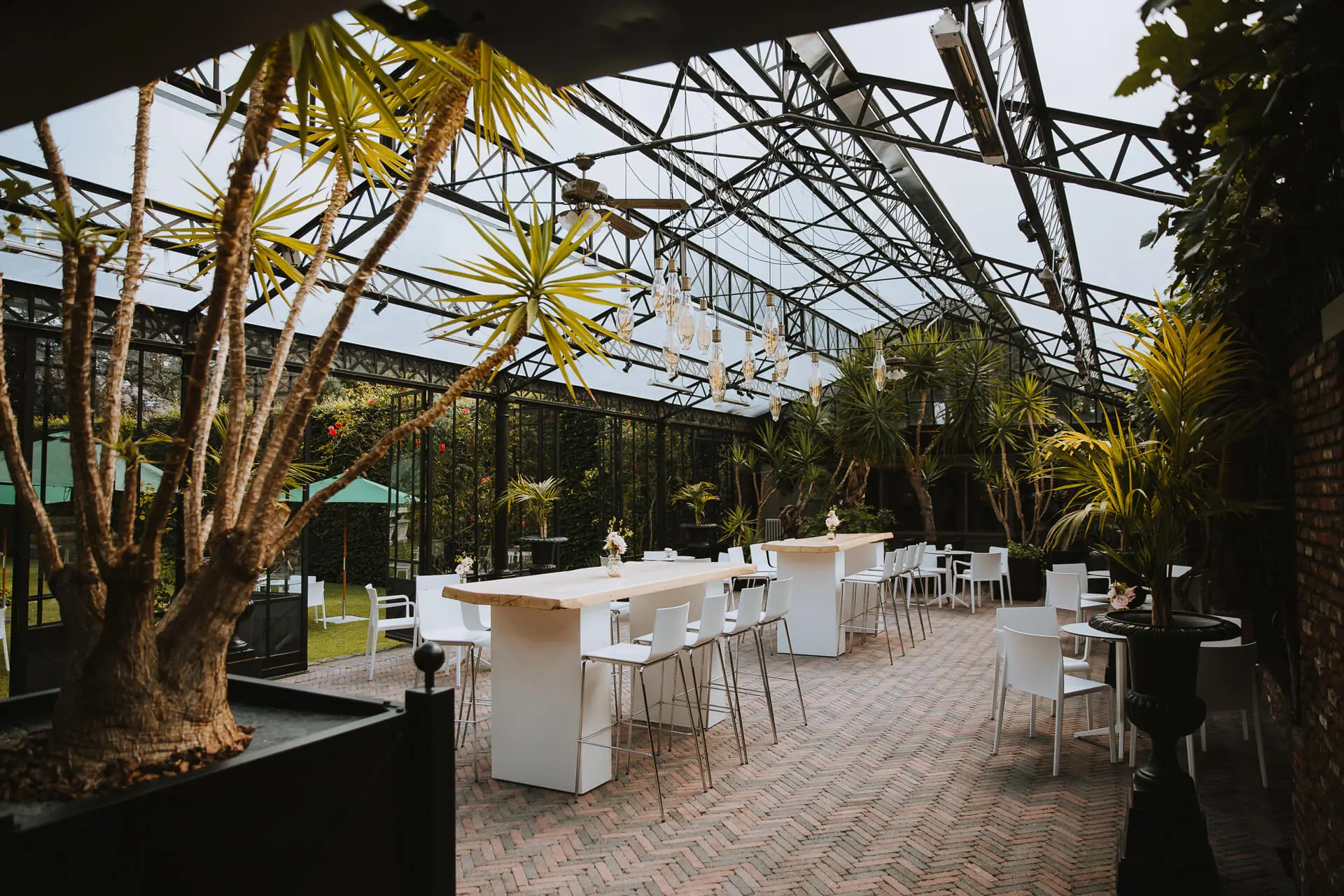 Orangerie van de grote zaal met hoge tafels, witte stoelen en palmen