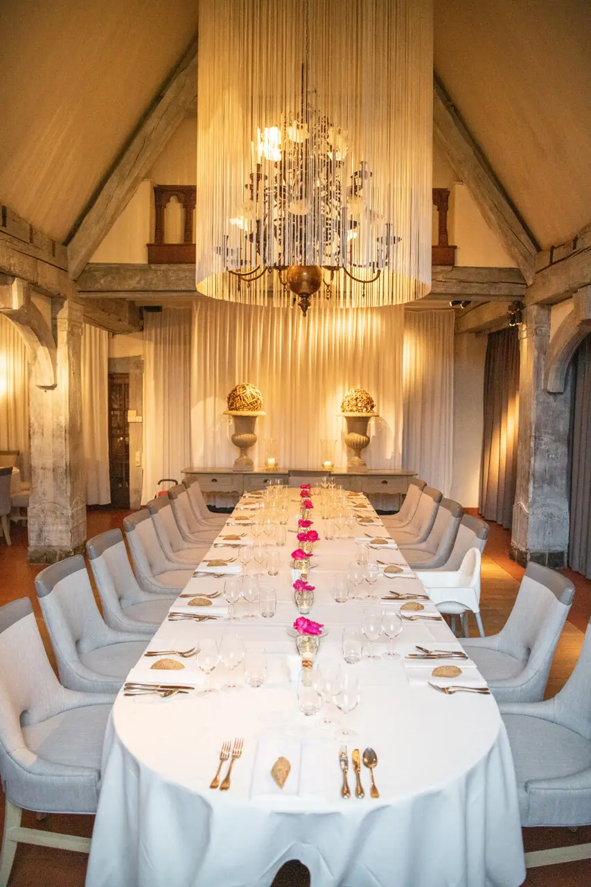 Lange ovale tafel gedekt voor een diner onder de kroonluchter in de kleine zaal