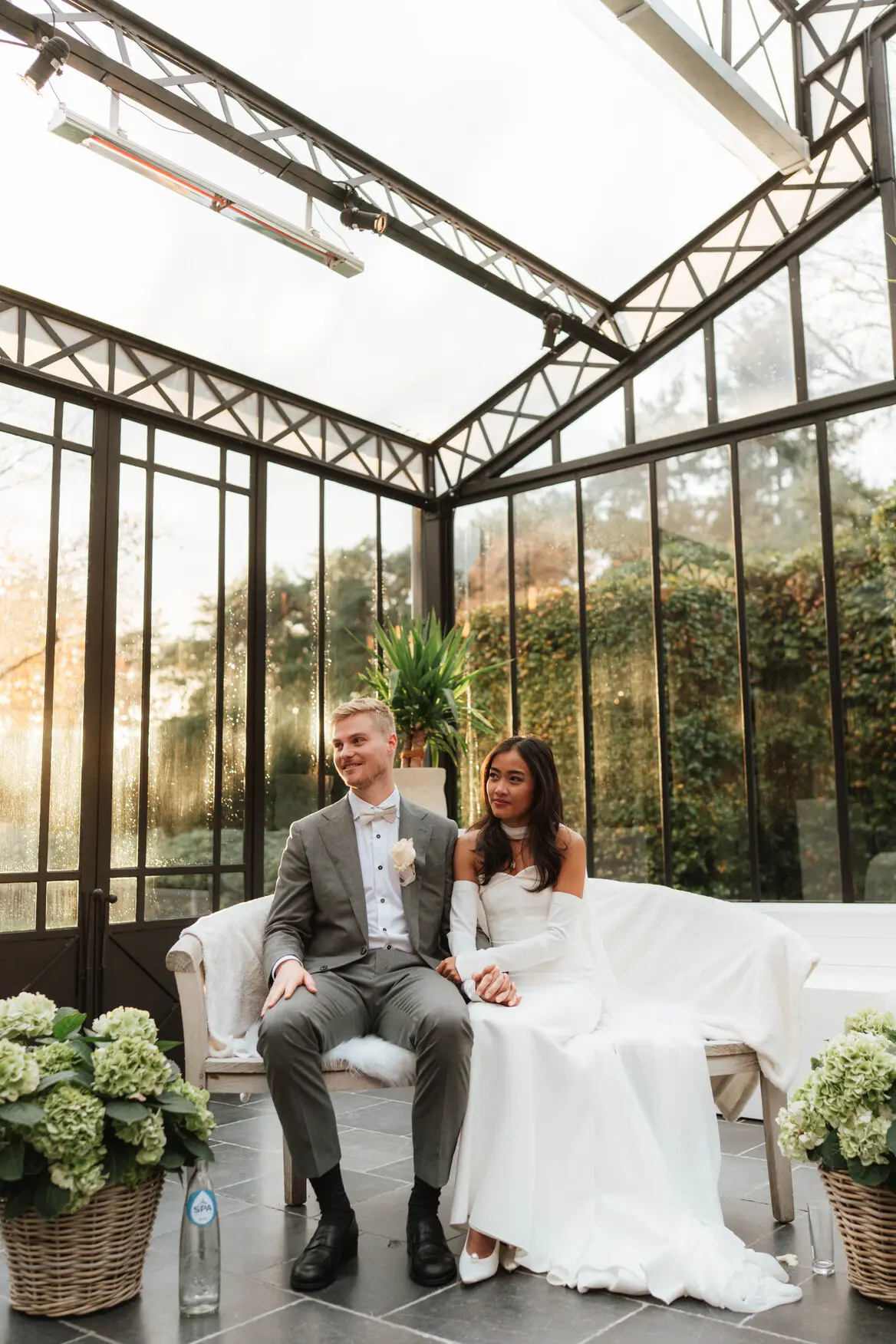 Bruidspaar op een witte bank in de orangerie van Alta Ripa