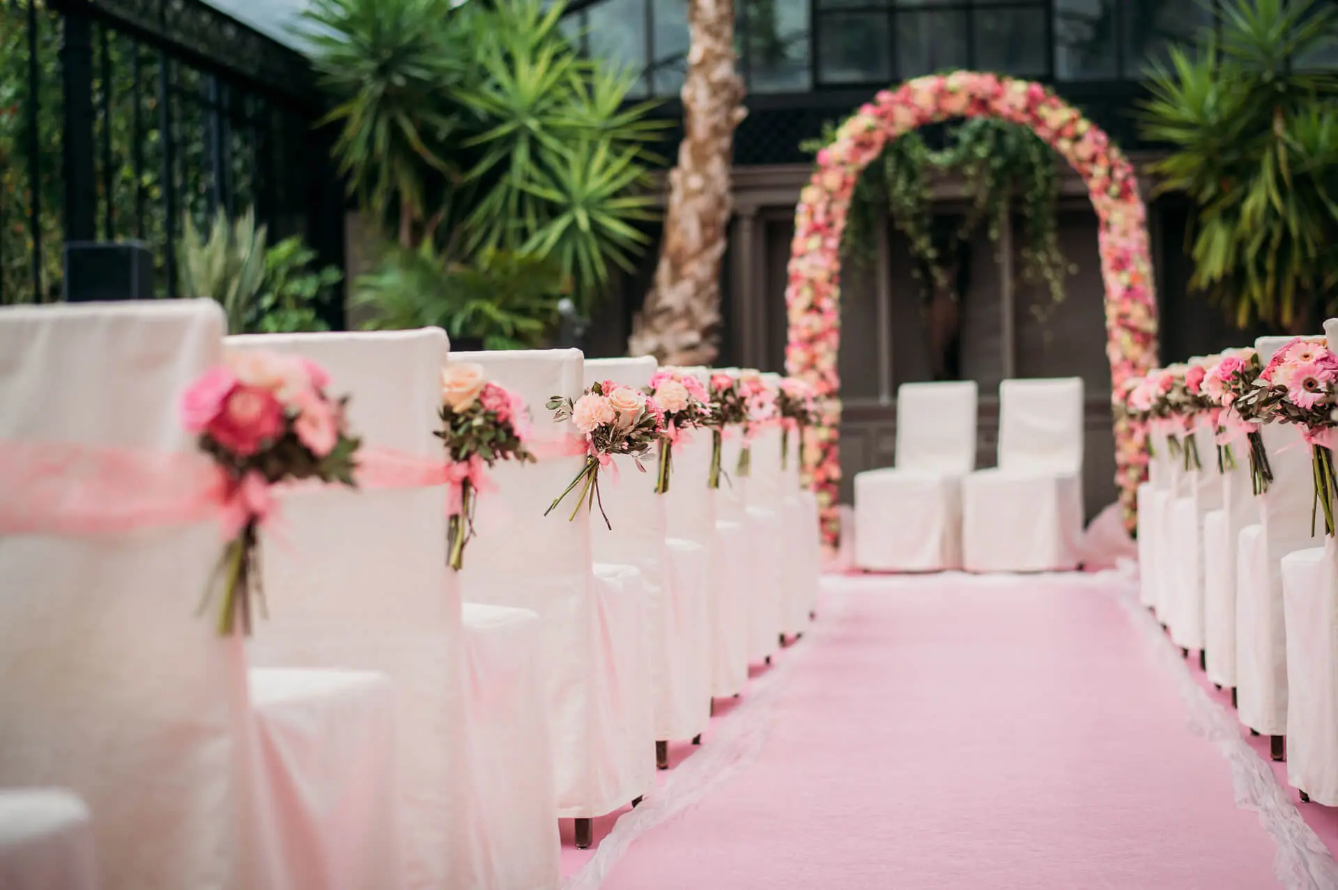 Ceremonie-opstelling in de orangerie met een roze loper en een bloemenboog