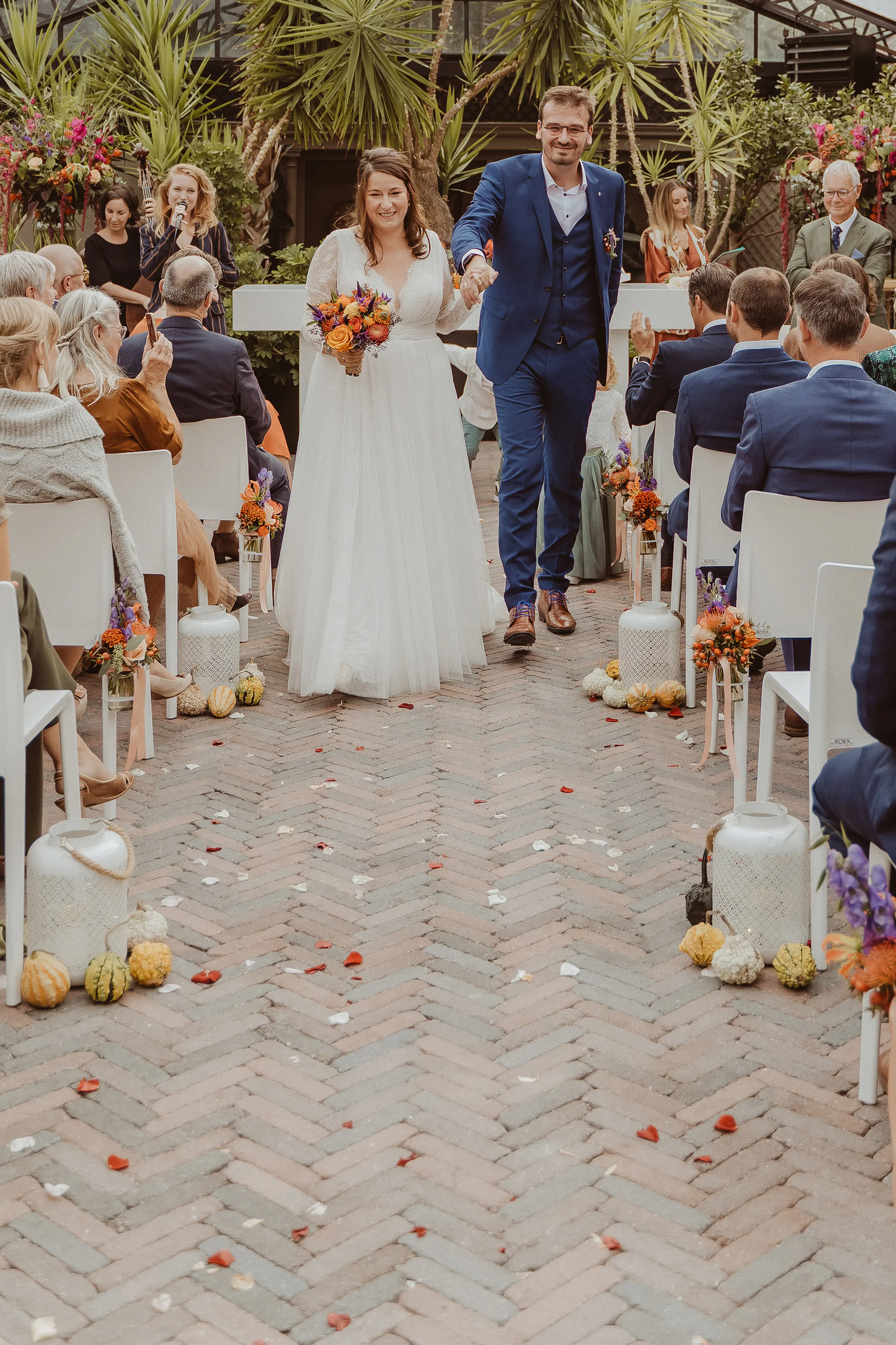 Bruidspaar loopt door het gangpad van een ceremonie in herfstthema