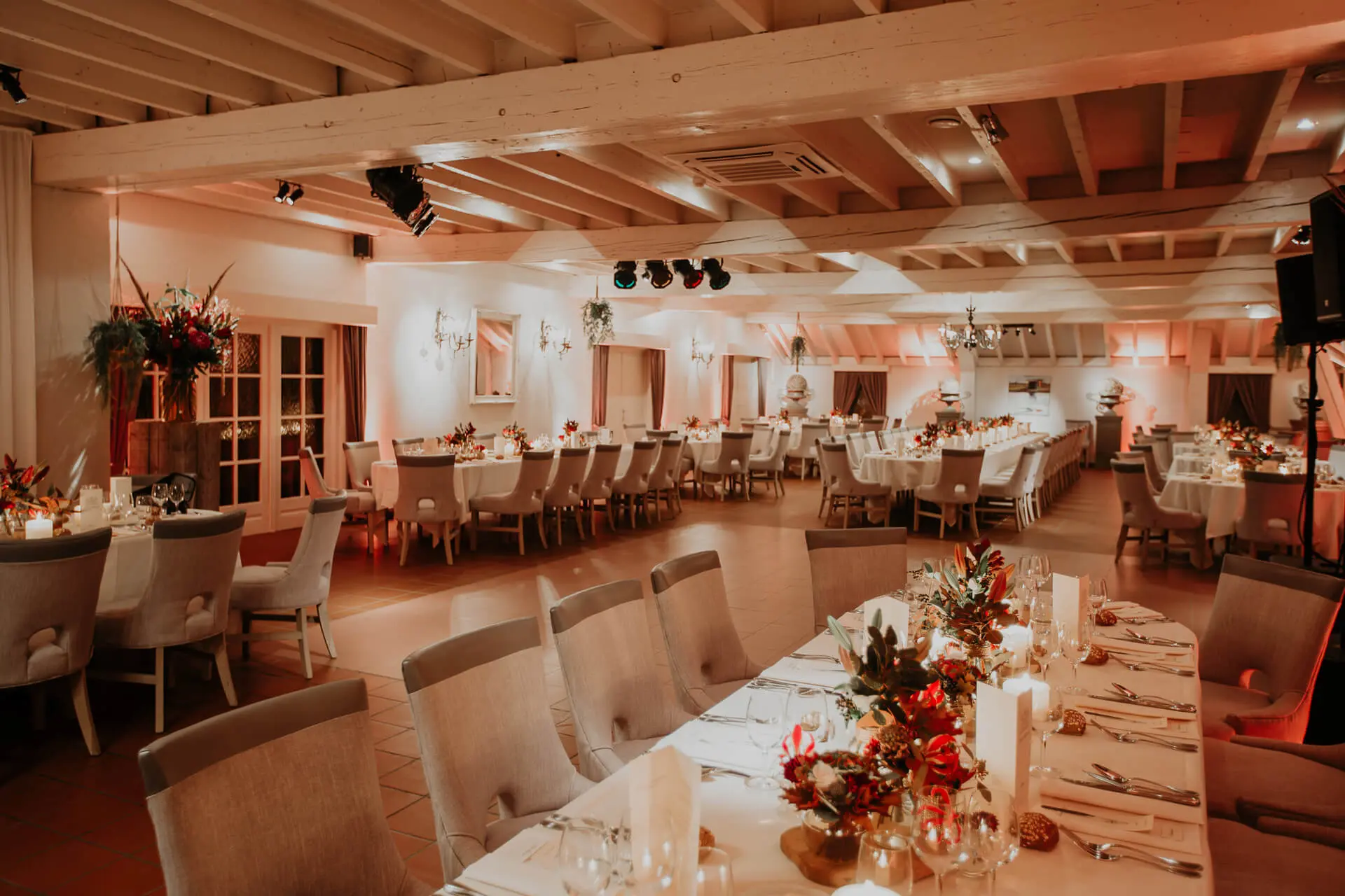 Kleine zaal gedekt voor een diner met lange tafels en herfstbloemstukken