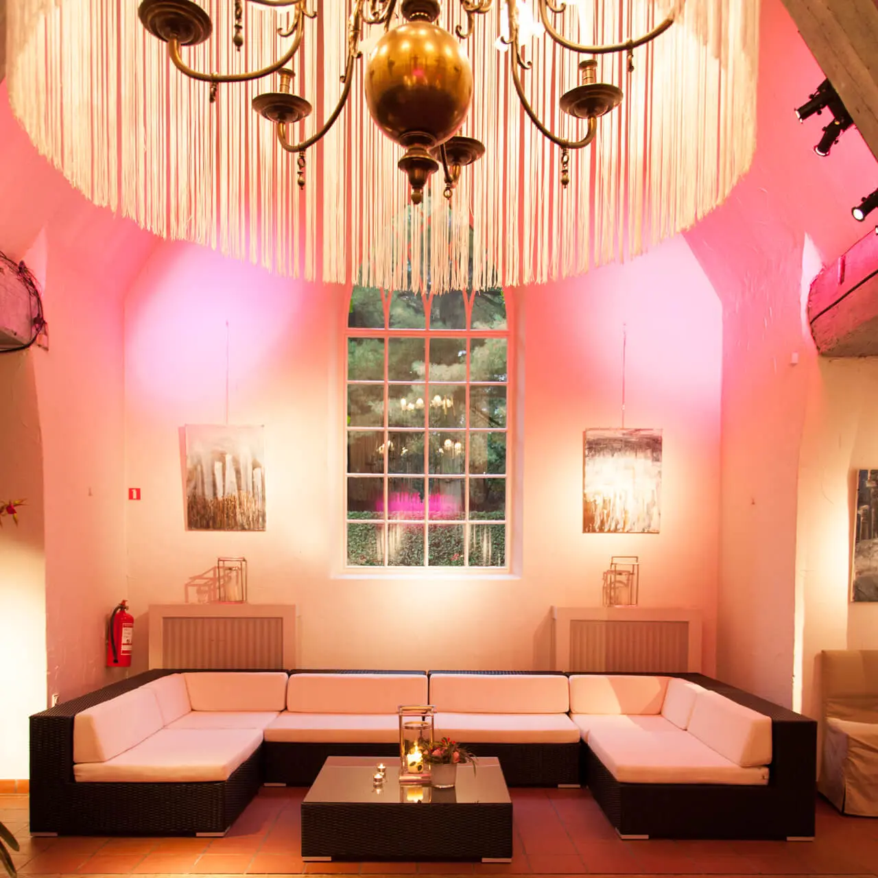 Loungezetel onder een grote kroonluchter in roze sfeerlicht