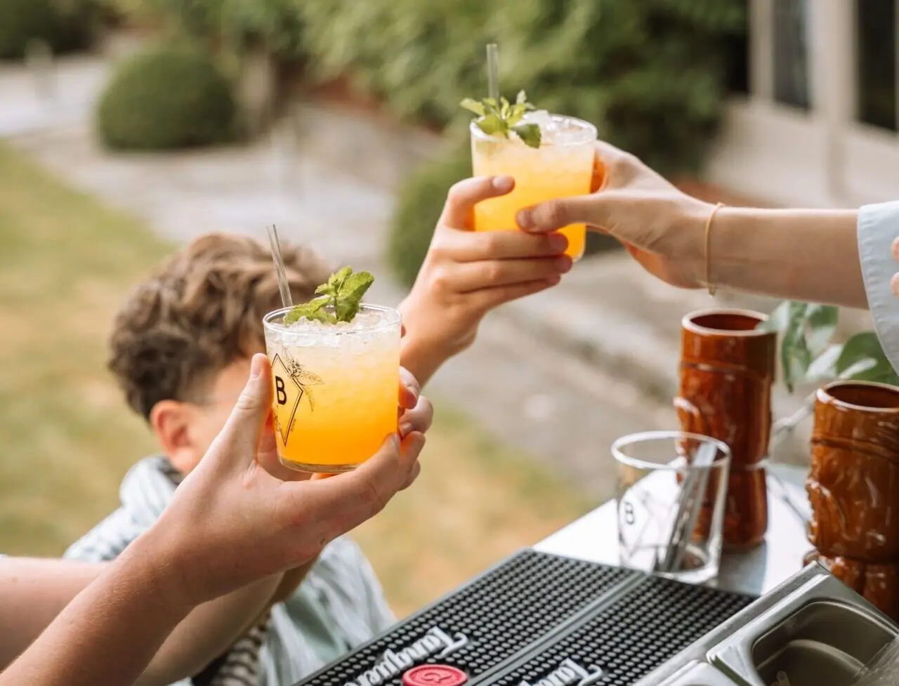 Gasten klinken met cocktails aan de buitenbar