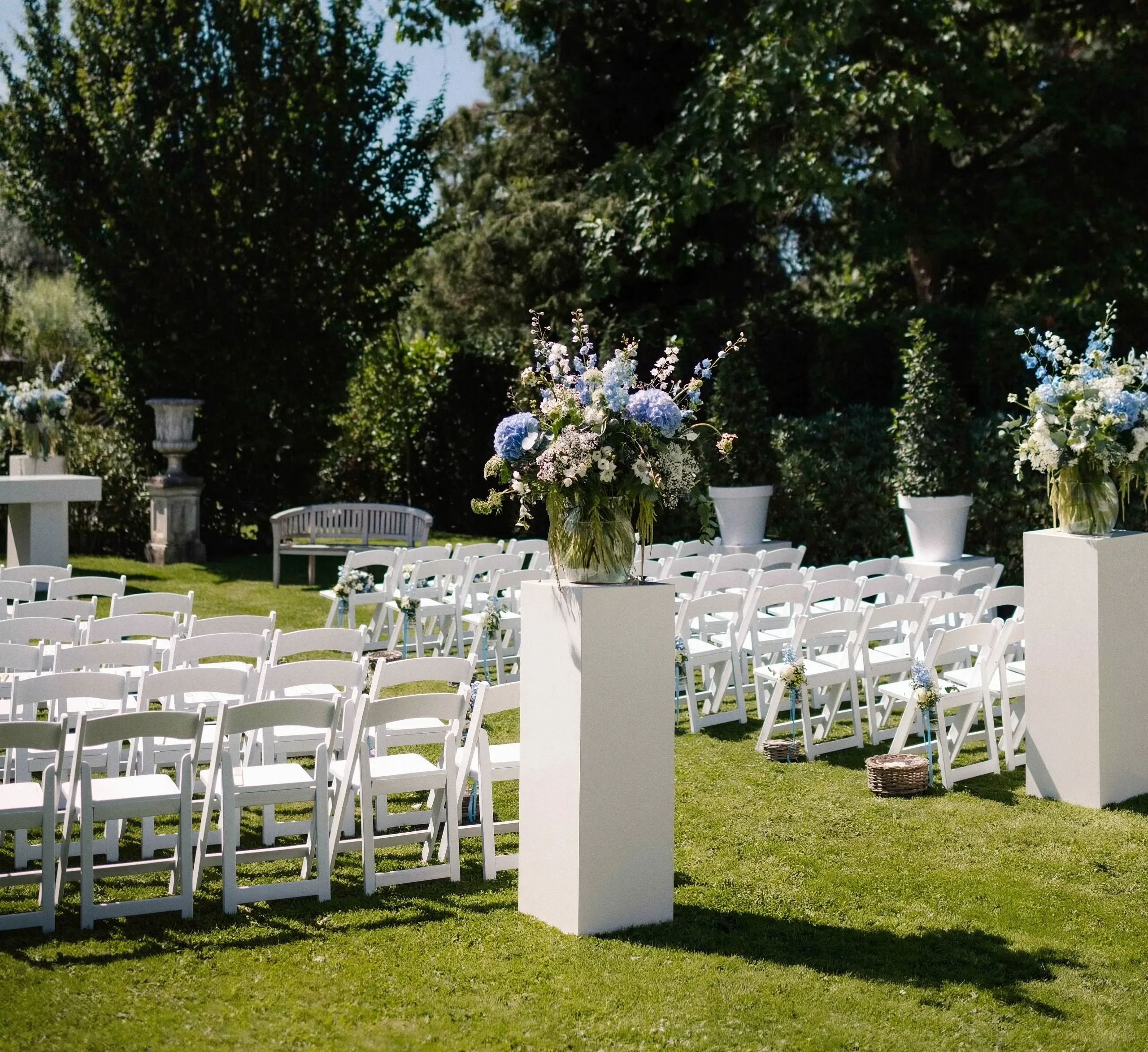 Ceremonie-opstelling met witte stoelen en bloemstukken in de tuin van Alta Ripa