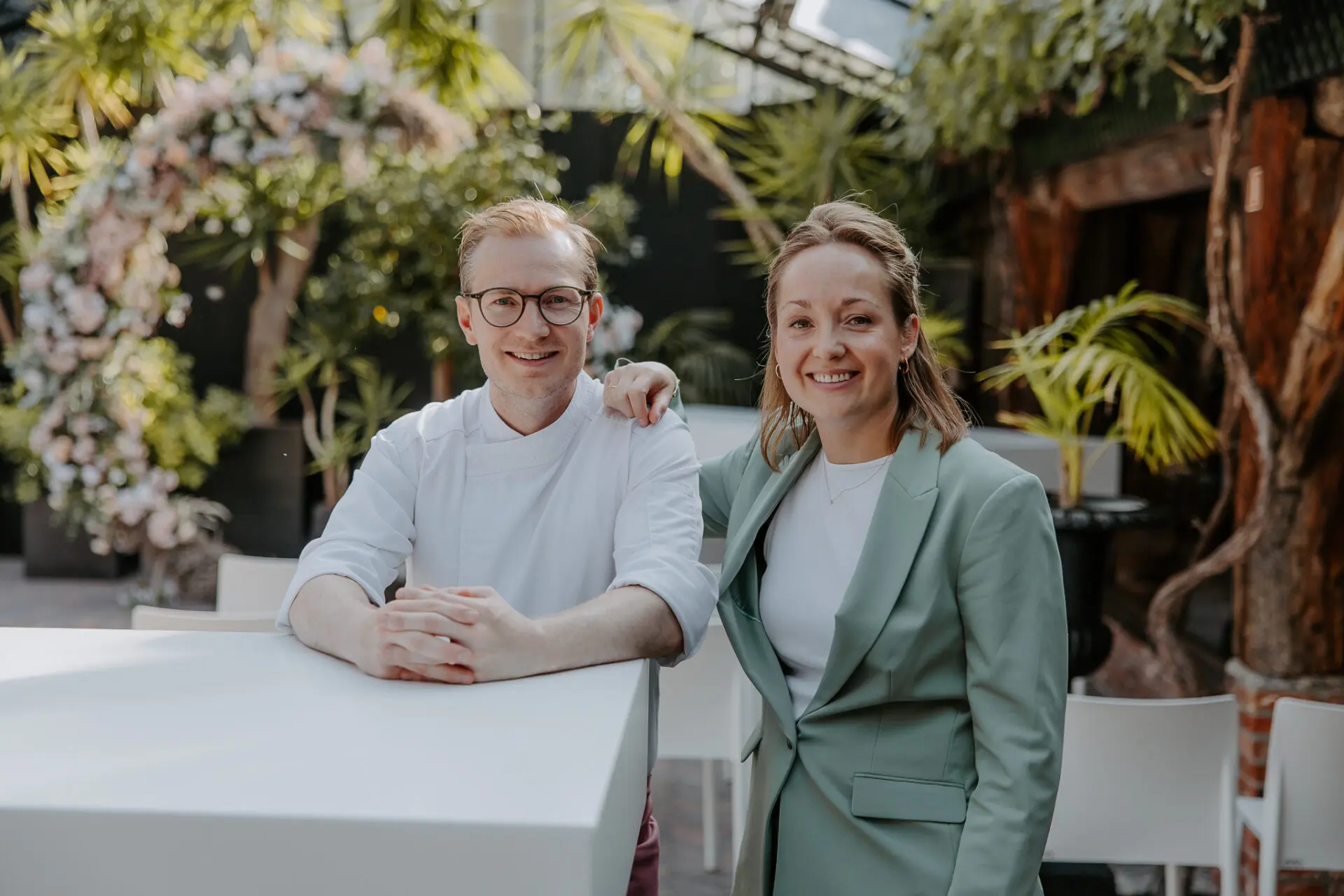 Steph en Dorothee Geenen in de orangerie naast een bloemenboog