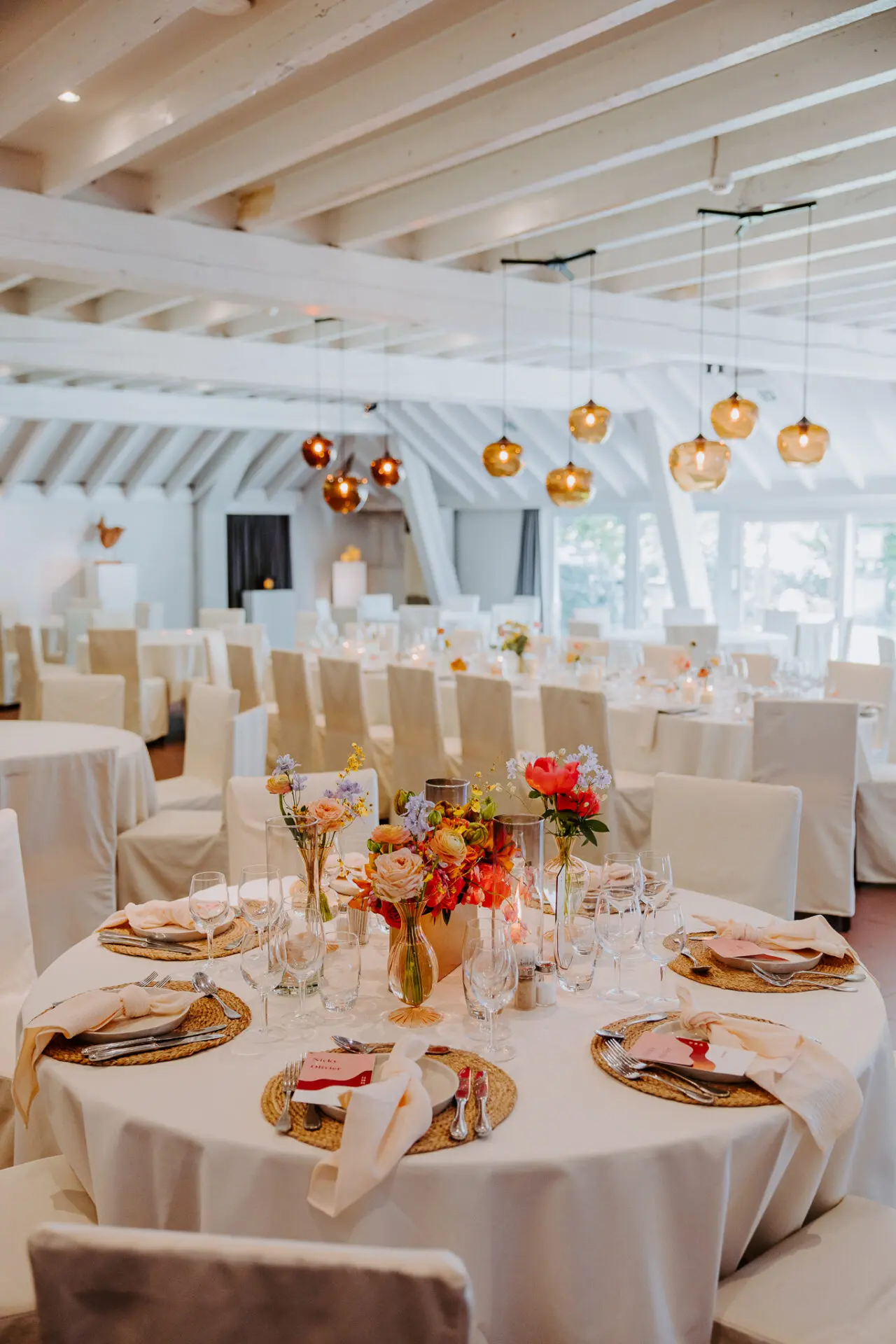 Feestelijk gedekte ronde tafels met bloemen in de feestzaal