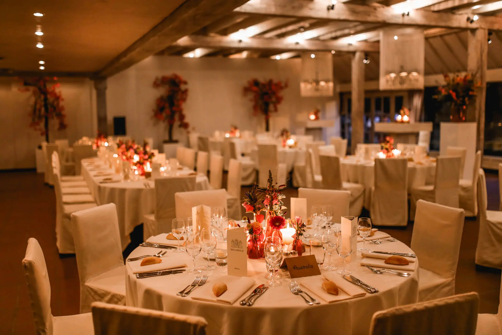 Gedekte ronde tafels met bloemstukken voor een diner in de grote zaal