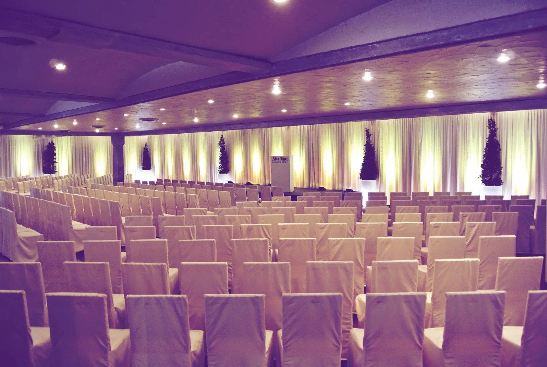 Grote zaal in theateropstelling met gesloten gordijnen voor de ramen
