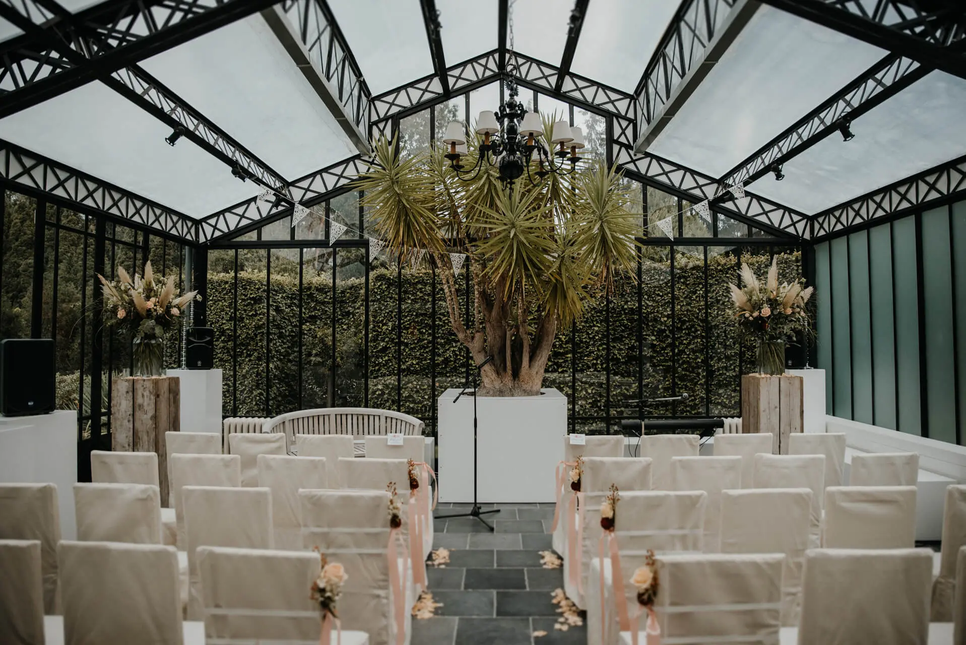 Orangerie van de kleine zaal opgesteld voor een ceremonie met stoelen in witte hoezen