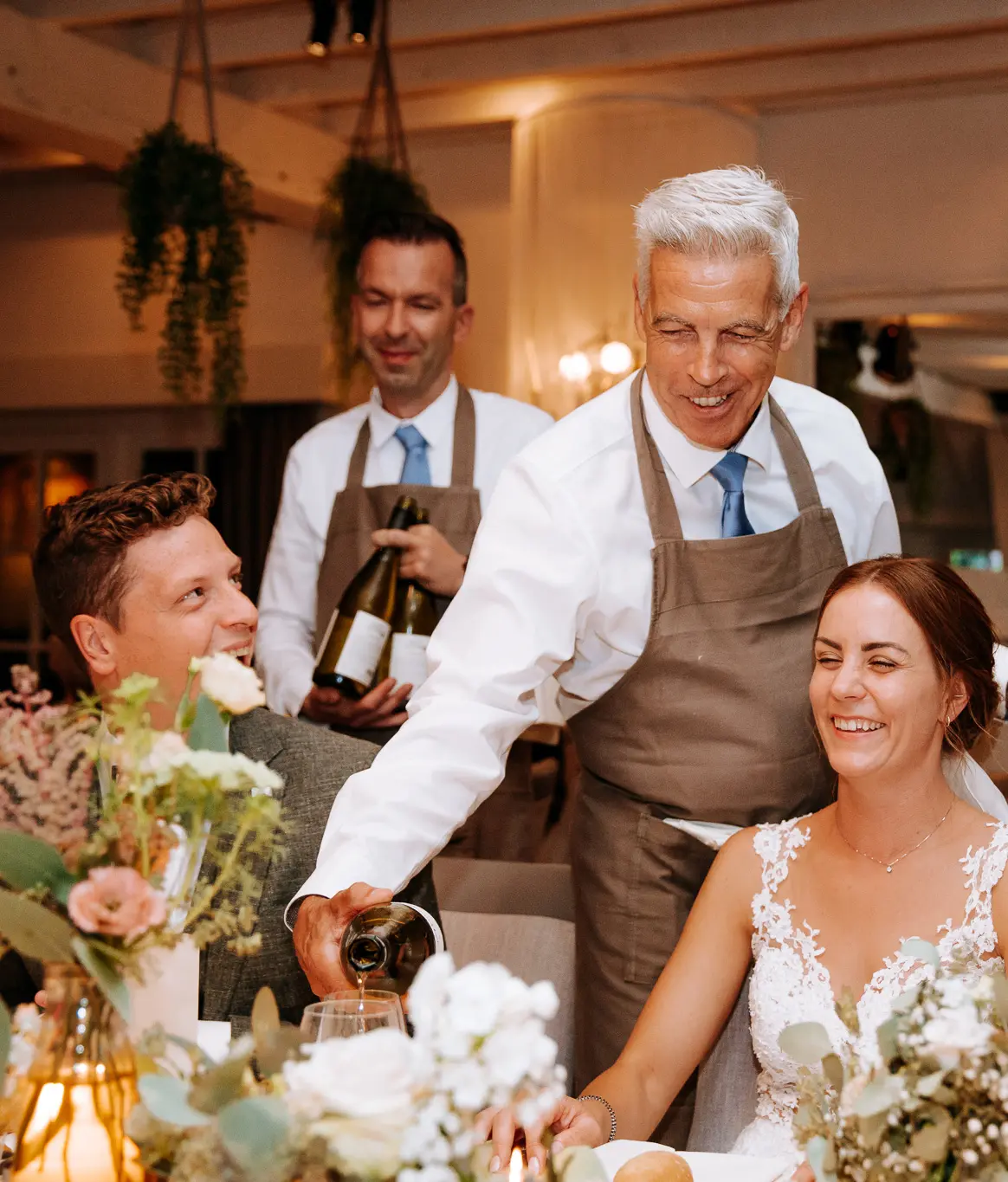 Bediening schenkt wijn in voor het bruidspaar aan tafel