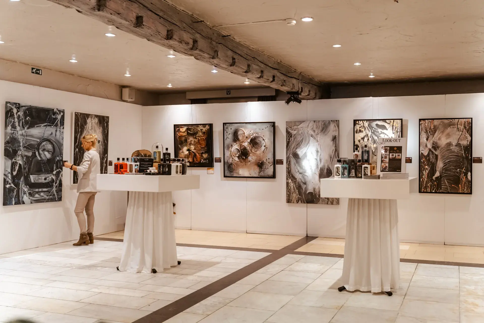 Kunsttentoonstelling met ingelijste werken en hoge tafels