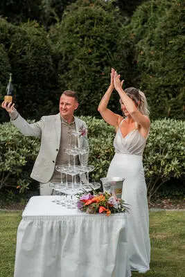 Bruidspaar juicht bij de champagnetoren in de tuin