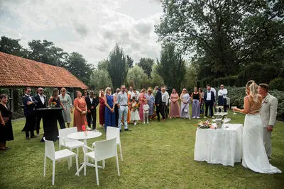 Gasten kijken in de tuin toe terwijl het bruidspaar de receptie opent